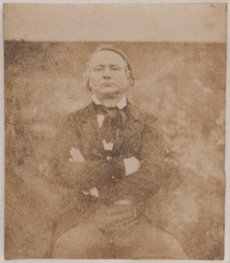 Victor Hugo assis de face, les bras croisés