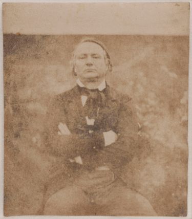 Victor Hugo assis de face, les bras croisés
