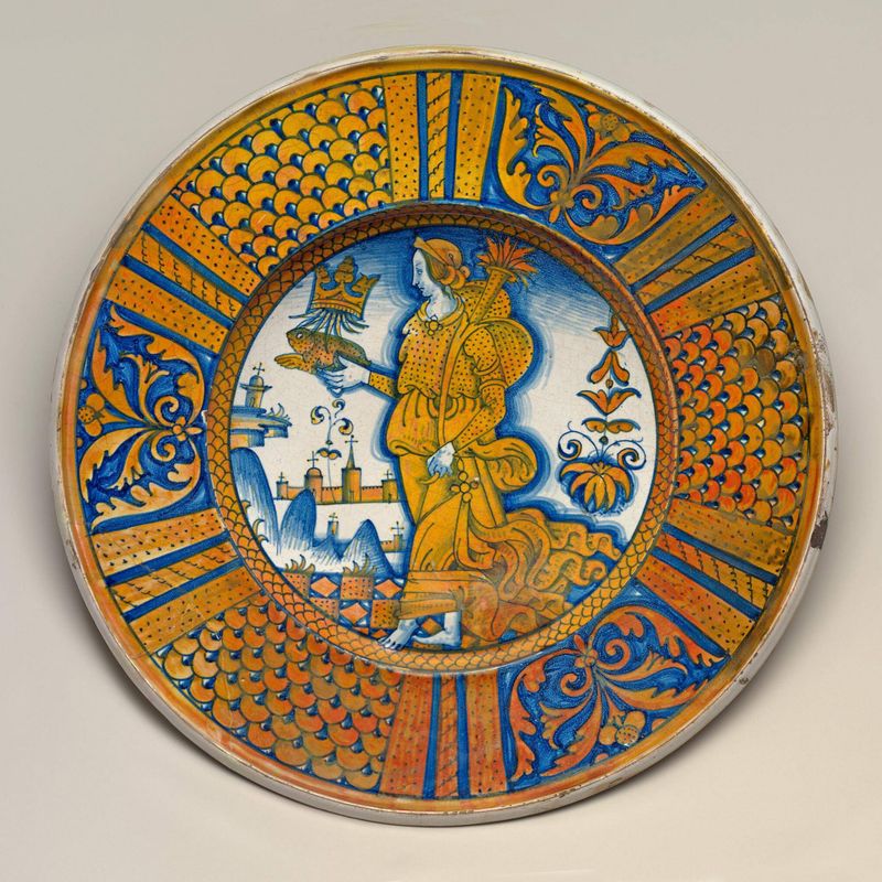 Large dish with segmental border of plant sprays and scale pattern; in the center, an emblematic female figure holding a crowned toad and cornucopia