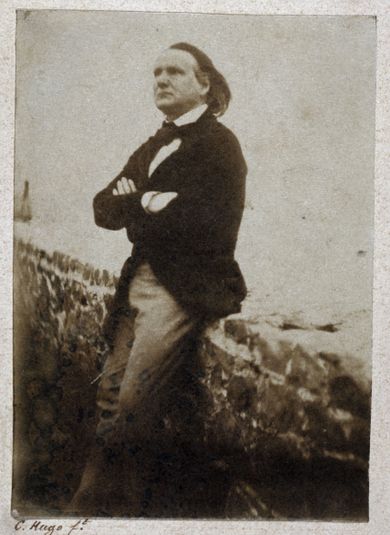 Victor Hugo appuyé à un muret, les bras croisés