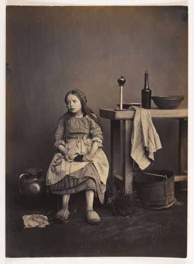 Petite fille assise près d’une table.