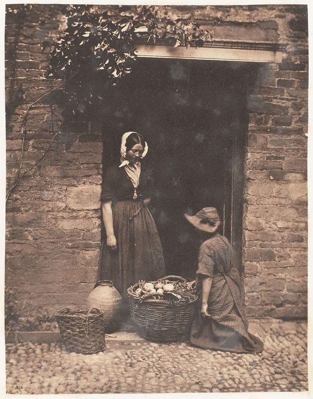 [Two Women, One Kneeling and One Standing, Looking into Basket Filled with Vegetables]