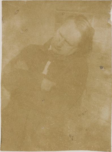 Victor Hugo adossé à un mur de briques, bras croisés, tête penchée vers la gauche