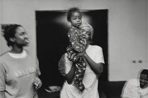 A young woman holds her baby brother high. Olive Branch Mission, Chicago.