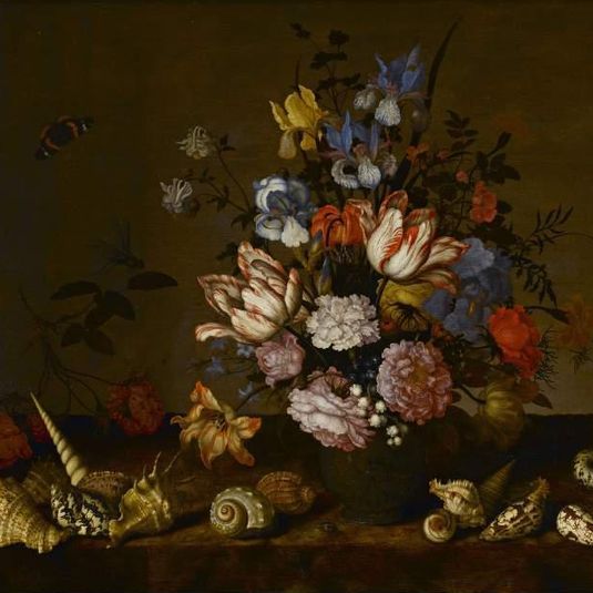 A vase of flowers with shells on a ledge